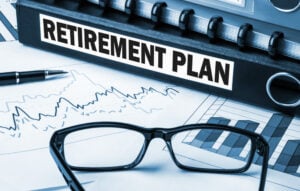 Retirement plan binder with financial charts and glasses, suggesting financial planning.