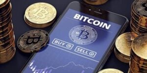 Smartphone displaying Bitcoin trading application amidst golden coins, questioning 'Is Bitcoin mining profitable?