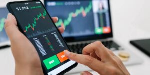 Person trading cryptocurrency on a smartphone with market charts in the background