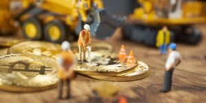 Miniature construction workers on Bitcoin coins representing the concept of cryptocurrency mining.