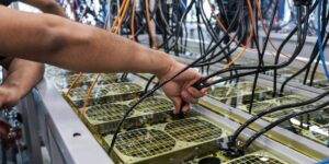 Hands adjusting cables on submerged ASIC miners using liquid cooling technology