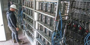 Technician inspecting rows of ASIC miners in a cryptocurrency mining facility.
