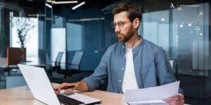 Business professional reviewing documents and working on a laptop in a modern office
