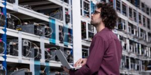 Technician analysing Bitcoin mining rigs in a large-scale facility.