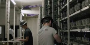 Technicians wearing hard hats inspect and maintain cryptocurrency mining rigs inside a high-performance data center, ensuring optimal efficiency and uptime.