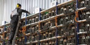 A technician wearing protective gear climbs a ladder to maintain and inspect high-density ASIC mining rigs in a large-scale cryptocurrency mining farm.
