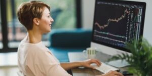 woman tracking cryptocurrency price charts on desktop monitor 