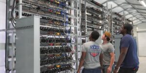 Group of workers inspecting cloud mining rigs inside a cryptocurrency facility.