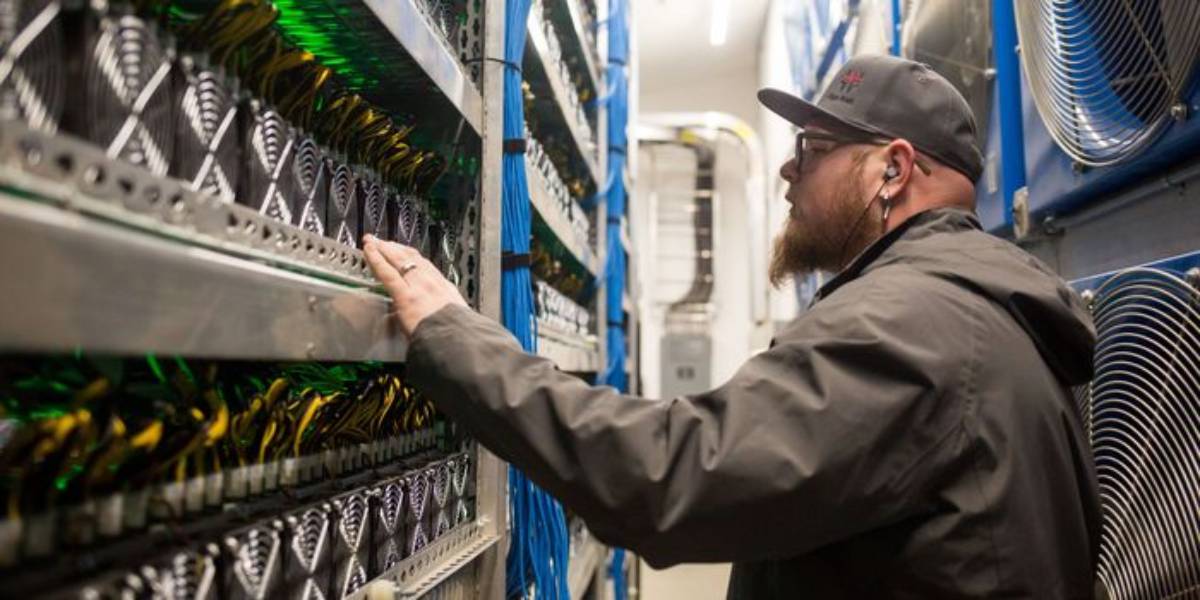 Technician inspecting bitcoin mining hardware in a cryptocurrency data centre.