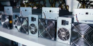 Row of ASIC bitcoin mining machines with cooling fans used for cryptocurrency mining.
