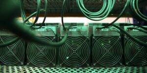 Row of ASIC computer connected by power cables inside a cryptocurrency mining facility.