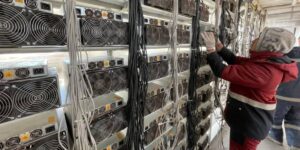 Technician setting up multiple ASIC mining machines in a large-scale cryptocurrency mining facility.