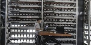 Technician managing rows of ASIC miners in a large-scale cryptocurrency mining facility.
