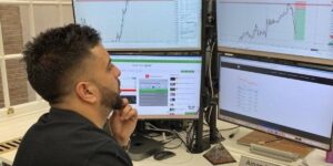 Trader analysing charts on multiple monitors, representing Payout Schemes, Mining Pools, and Latency Considerations in cryptocurrency mining.