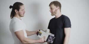 Two people holding an ASIC miner together, illustrating Getting Started with bitcoin mining with ASICs.