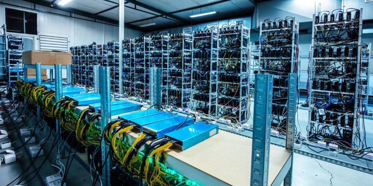 Rows of computer mining rigs and power units in an industrial server room.