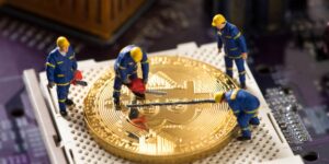 Bitmain miners concept image showing miniature workers mining a large Bitcoin coin on a computer chip