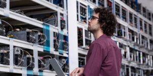 Technician inspecting cryptocurrency mining equipment with a laptop
