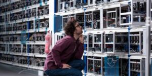 Technician inspecting rows of cryptocurrency mining equipment in a large facility