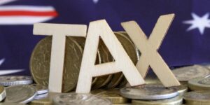 Wooden tax letters placed on coins with an Australian flag in the background