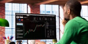 Person viewing a spot trading chart on a desktop monitor in a modern office setting