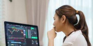 Woman studying cryptocurrency price charts on a computer to learn how to read crypto charts.