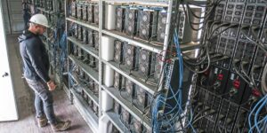 Technician inspecting ASIC miners inside a cryptocurrency mining hosting facility