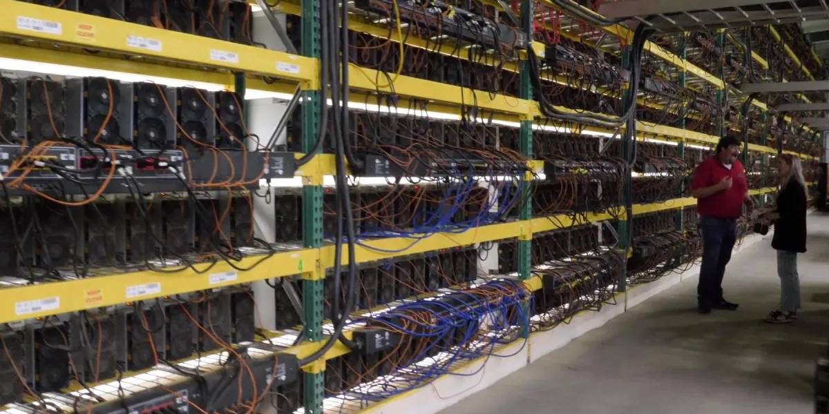 Large cryptocurrency mining facility with ASIC miners and technicians reviewing hosting operations